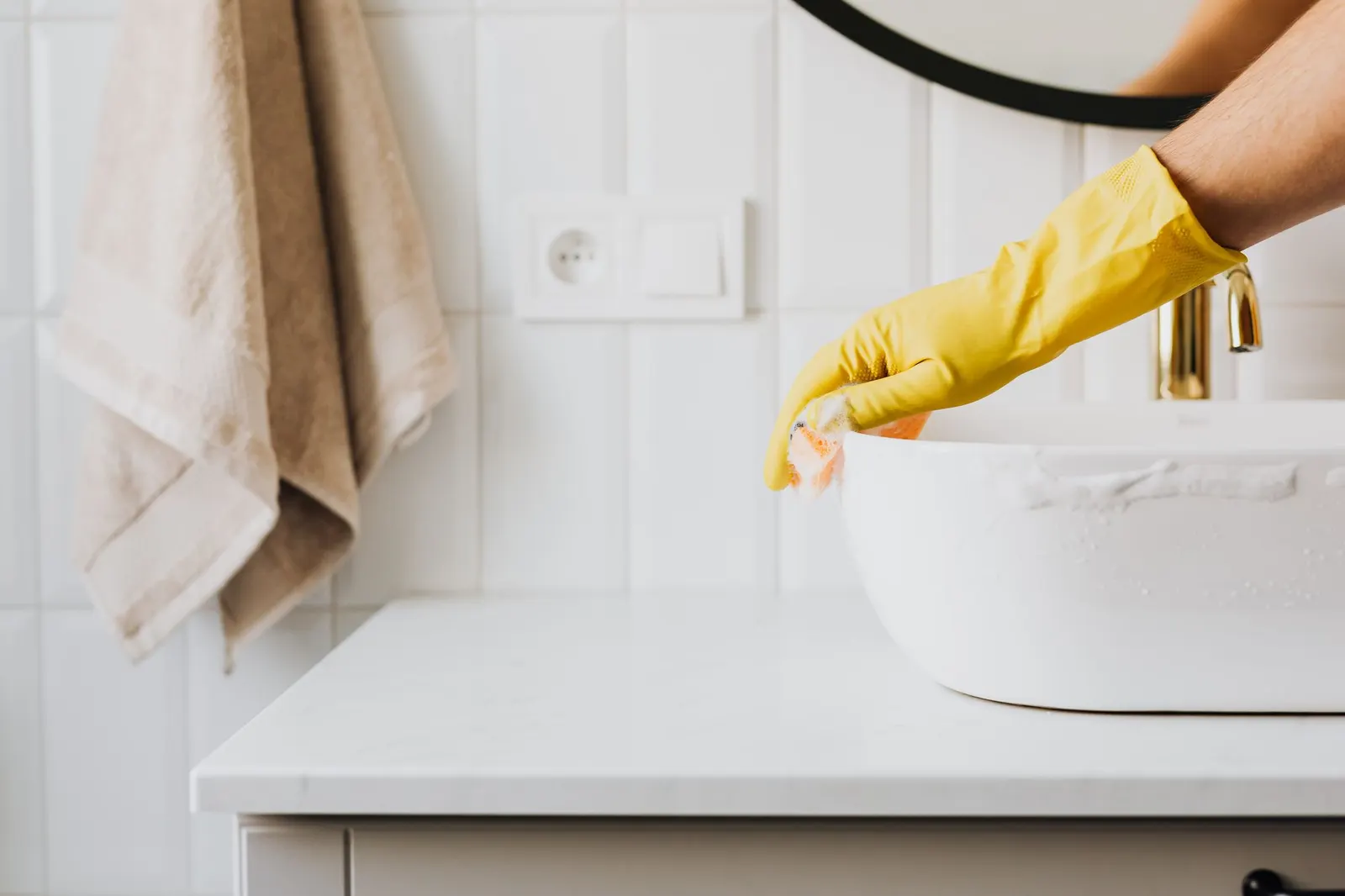 Gloved hand wiping the rim of a white bathroom basin