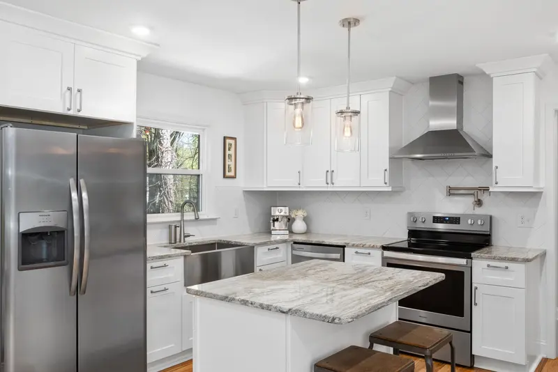 White kitchen with a marble island and stainless steel appliances