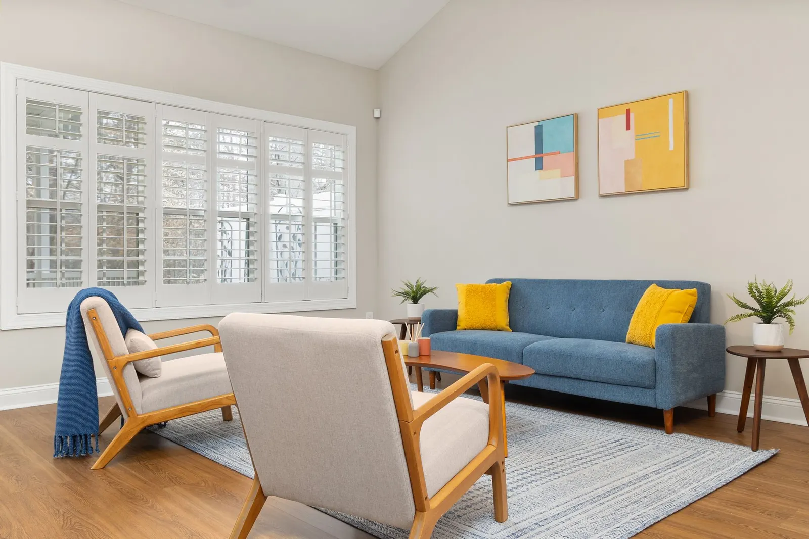 Tidy living room with a blue sofa, an armchair and white window shutters
